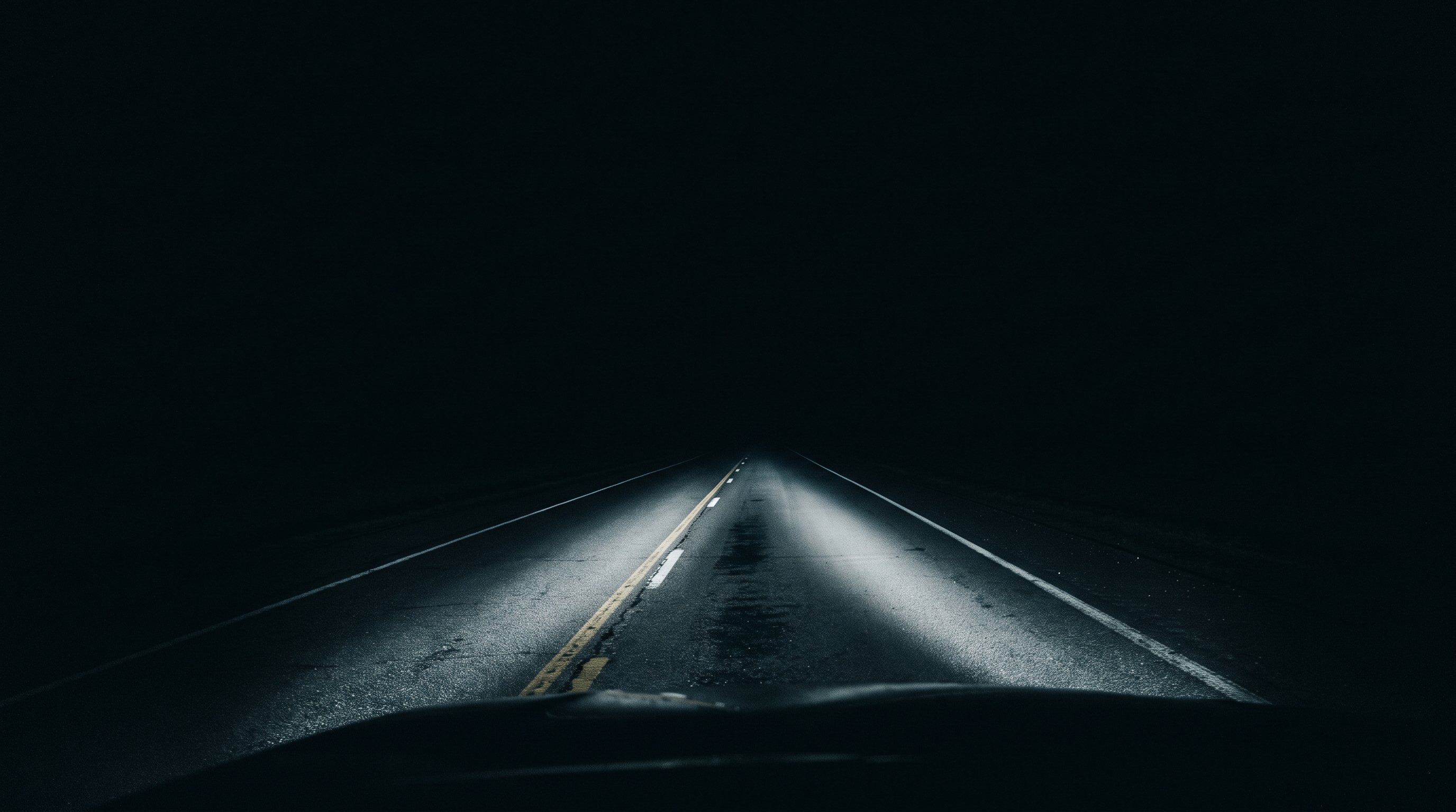 Headlights lighting an empty road at night